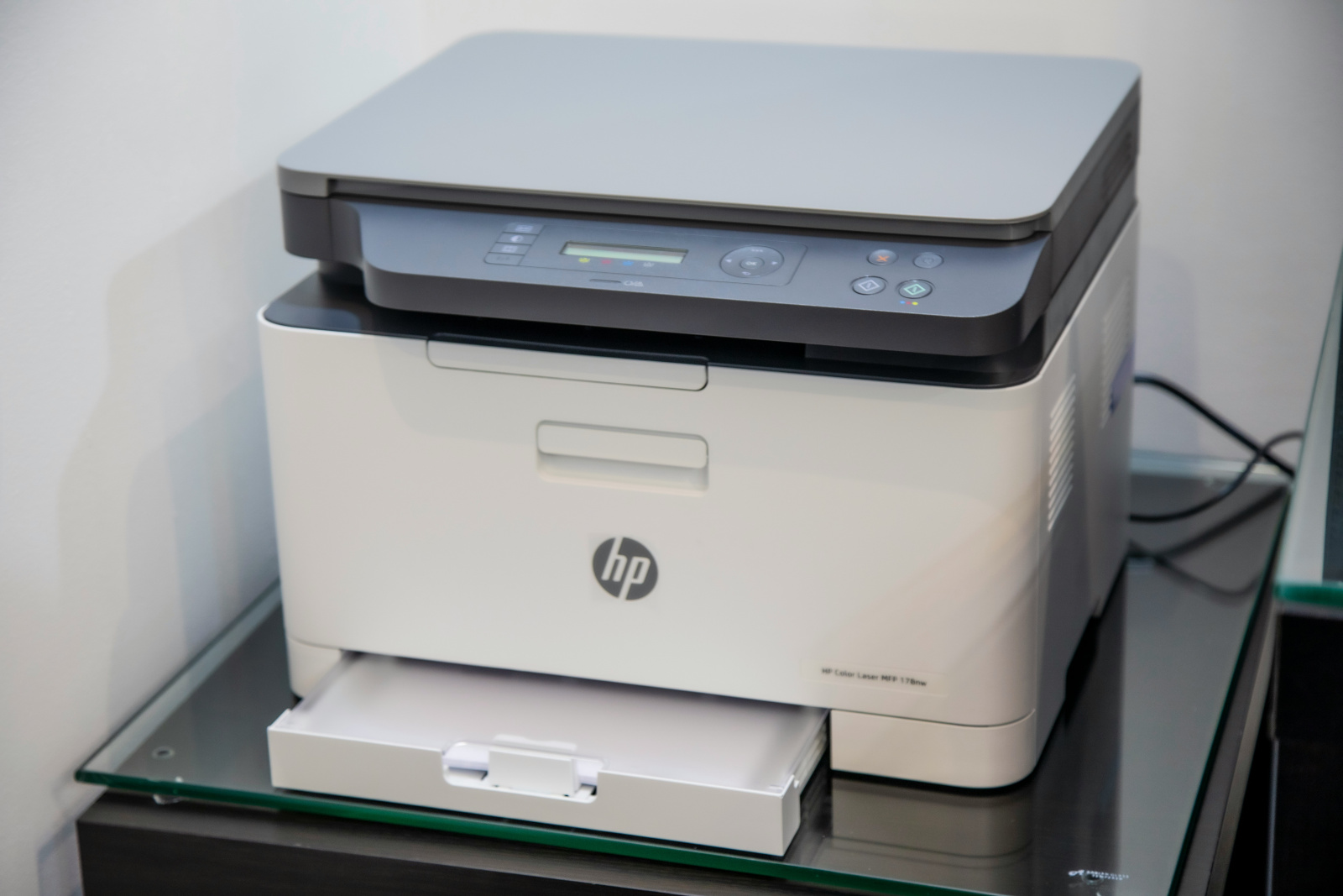 Imprimantă laser HP pe o suprafață din sticlă.